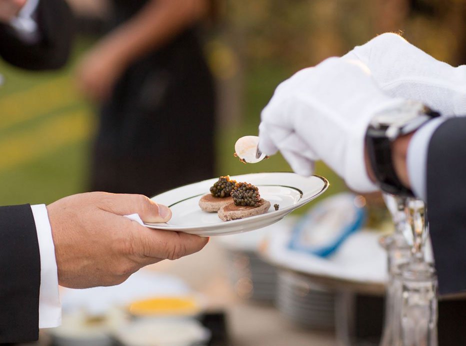 white gloved hands serving caviar on a plate